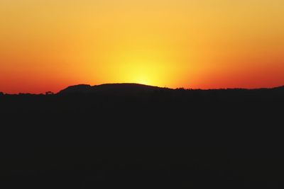 Scenic view of silhouette landscape against orange sky