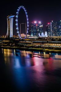 Illuminated bridge over river at night