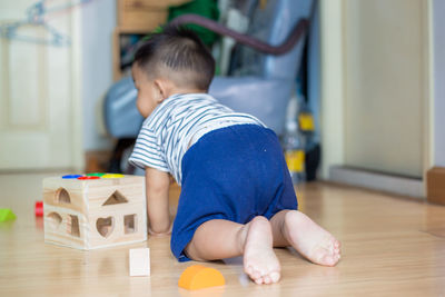 Rear view of cute boy playing on floor at home