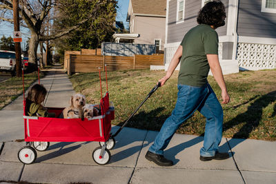 Dad pulling a wagon with daughter and two pet dogs riding inside