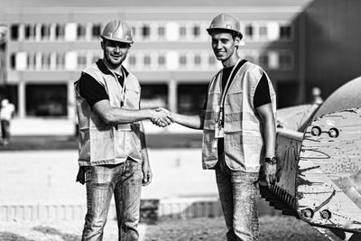 Manual workers shaking hands while working outdoors