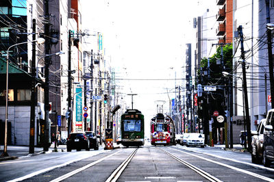 Cars on railroad track in city against clear sky