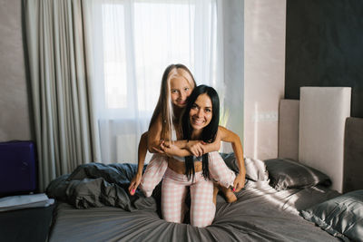 Mom and daughter have fun on the bed in the morning. piggy back