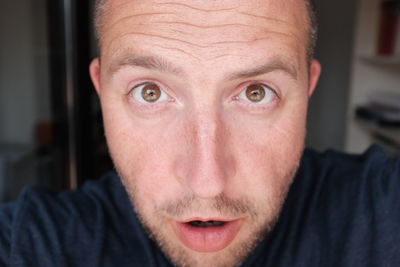 Close-up portrait of shocked man at home