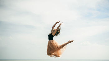 Woman dancing over sea against sky