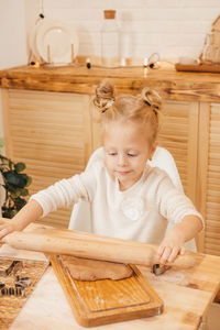 Girl's hands rolls out ginger dough with a rolling pin in the kitchen. 