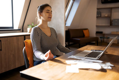 Side view of young businesswoman working on table