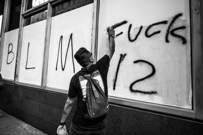Full length of boy standing against graffiti wall