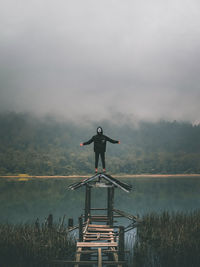 Man standing by lake against sky