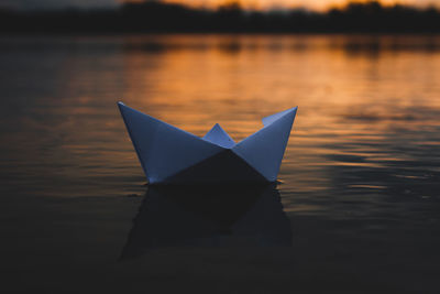 Close-up of paper boat floating on lake during sunset