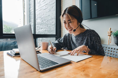 Young woman using phone while sitting on table