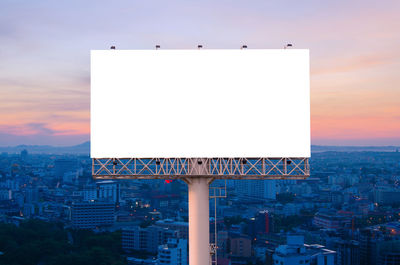 Information sign on buildings in city against sky during sunset