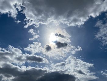 Low angle view of sunlight streaming through clouds