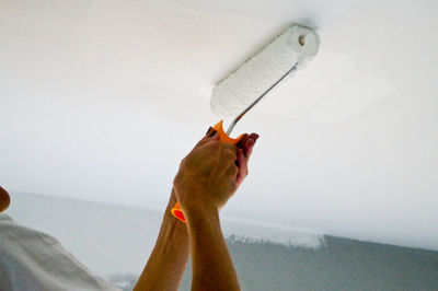 Cropped image of woman painting ceiling at home