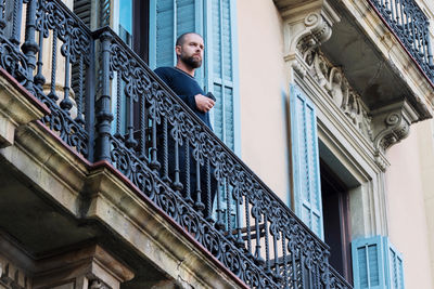 Man standing on the balcony on historical building holding his phone