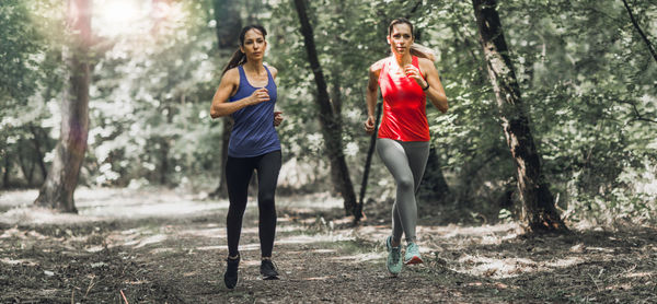 Full length of female athletes running in forest