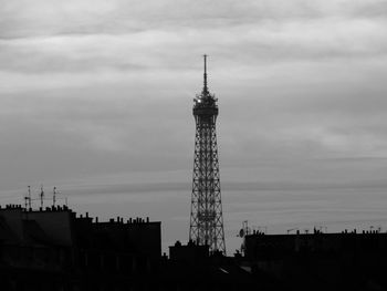 Low angle view of communications tower against cloudy sky