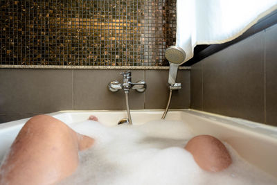 Low section of man in bathtub at home