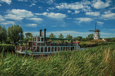 Old steamboat and windmill in canal with bushes near damme. a charming country village in belgium.