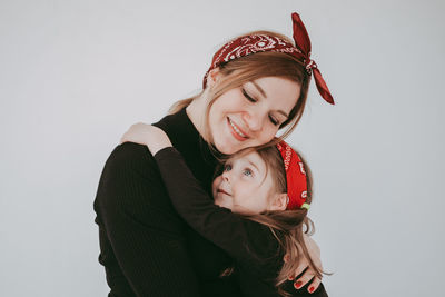 Smiling mother and daughter embracing in studio