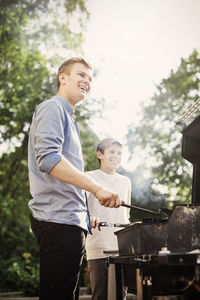 Happy brothers barbecuing at yard