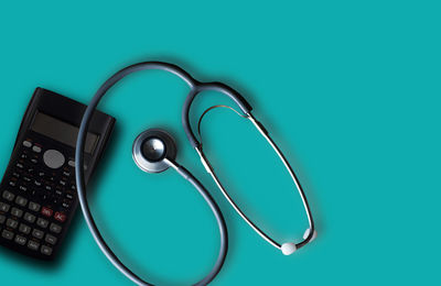 High angle view of stethoscope with key on blue background
