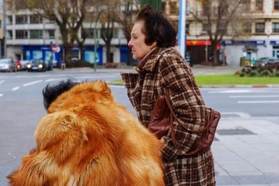 Side view of young woman with dog on street