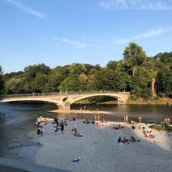 People by lake against sky