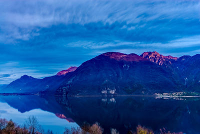 Scenic view of lake and mountains against blue sky