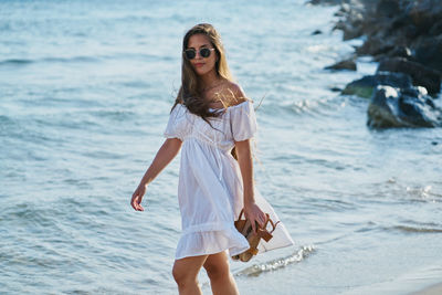 Young woman wearing sunglasses standing at beach