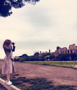 Woman photographing on field against sky