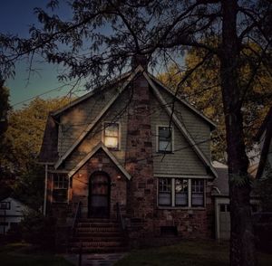 House amidst trees and buildings against sky