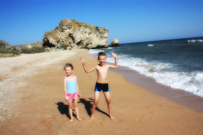 Full length of shirtless boy on beach against clear sky