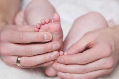 Cropped hands of woman touching feet of baby