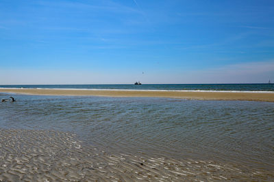 Scenic view of beach against blue sky