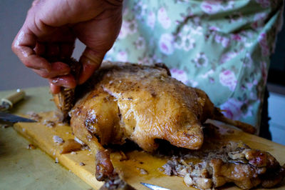 Cropped image of hand cutting roasted duck on board