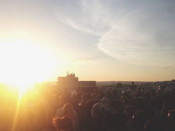 Crowd of people in city against sky during sunset