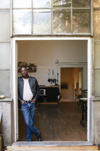 Businessman with legs crossed standing at doorway of workplace