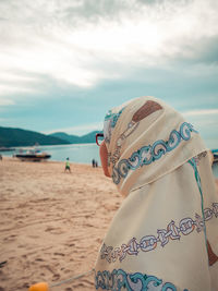 Rear view of woman on beach against sky