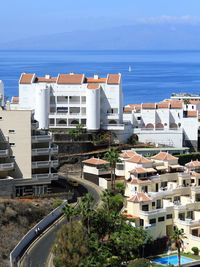 Buildings by sea against blue sky