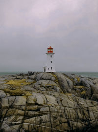 Lighthouse by sea against sky