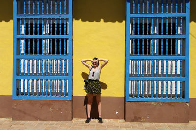 Young woman standing against building during sunny day