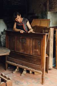 Female restorer working with ancient wooden furniture in workshop