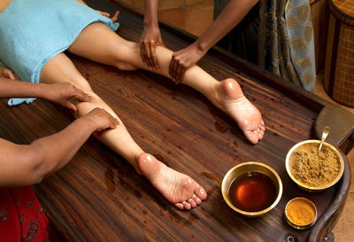 Cropped image of women massaging female customer leg at spa