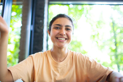 Portrait of smiling young woman against window