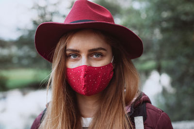 Portrait of beautiful young woman wearing hat with face mask