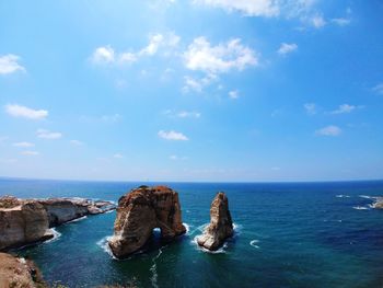 Rock formations in sea against blue sky