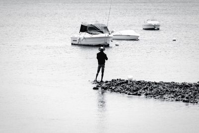 Rear view of fisherman fishing at lakeshore