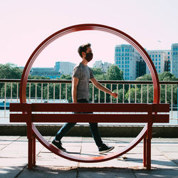 Rear view of man standing by railing against sky