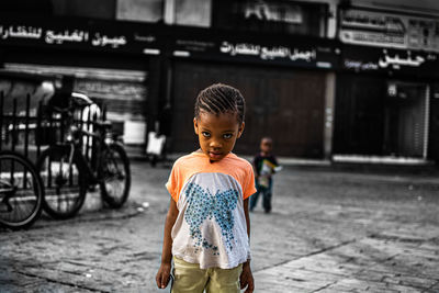 Portrait of boy standing on street in city